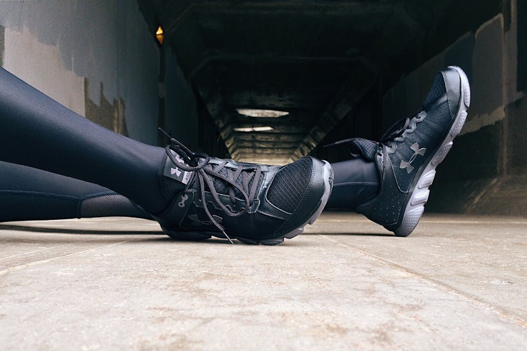 Close-up of a runner's legs in athletic wear resting in an urban tunnel.