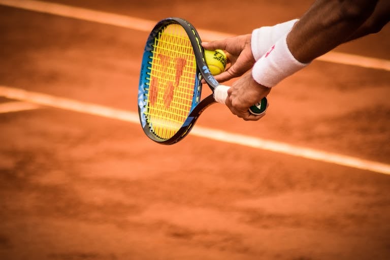 Close-up of a tennis player preparing to serve on a clay court in Montevideo.