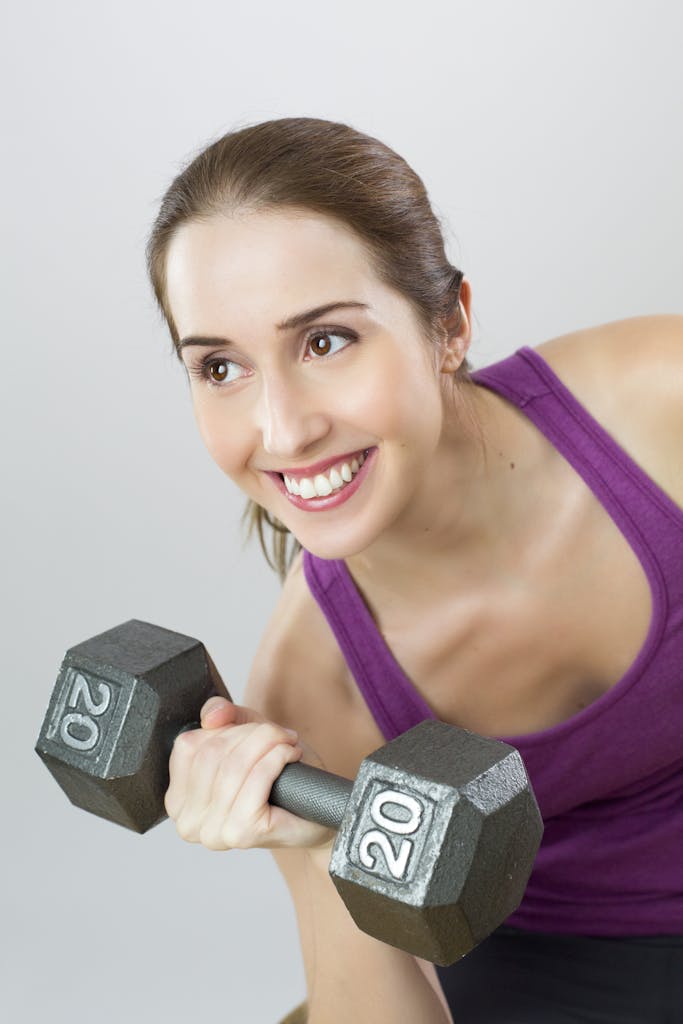 Young woman exercises with 20 lb dumbbell, showing strength and positivity.